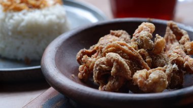 Kil tabakta kızarmış tavuk derisi ve masada pilav..