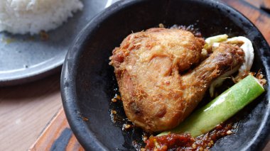 Kil tabakta sambal ve salatalıklı geleneksel Endonezya kızarmış tavuğu, pirinç ve buzlu çayla servis edilir..