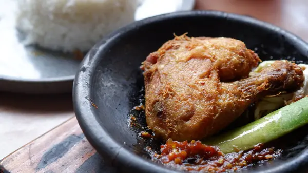 Kil tabakta sambal ve salatalıklı geleneksel Endonezya kızarmış tavuğu, pirinç ve buzlu çayla servis edilir..