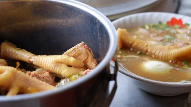 Chicken feet soup with shredded chicken, chicken feet, eggs, sliced cabbage, vermicelli in broth. Indonesian food. clipart