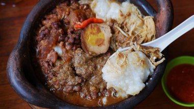 Üstü doğranmış tavuk, pindang yumurtası, tofu, krecek ve kil çömlek üzerinde meyveli Gudeg lapası. Gudeg, Jogja 'nın geleneksel mutfağıdır.. 
