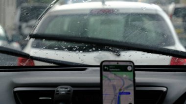 Sürücü yoğun yağmurda Google Maps kullanarak trafik sıkışıklığında araba kullanıyor. Sydney, 11 Mayıs 2025.