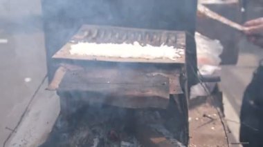 Satıcı eski bir odun sobasıyla kue rangi pişiriyor..