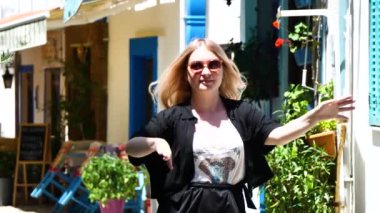 Yunan Rhodes şehrinin sokaklarında güneş gözlüklü ve mavi elbiseli genç bir kadın.