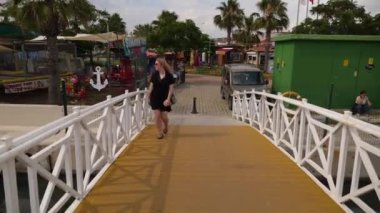 Siyah elbiseli kız gezinti güvertesinde yürüyor.