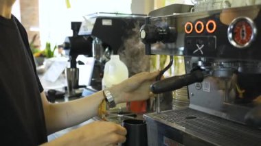 Kahve için süt buharı yapan barista ve buhar kolunu temizliyor. Kapatın. Yüksek kaliteli FullHD görüntüler