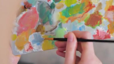Kız elleri boyaları palette fırçayla karıştırıyor. Yüksek kalite 4k görüntü