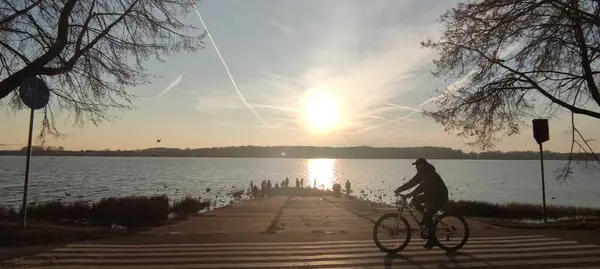 Erkek, baharda ya da yazın gün batımında göl kenarında bisiklet sürüyor. Renkli manzara nehri. Spor ve seyahat. Bisiklet sürmek. Yüksek kalite fotoğraf