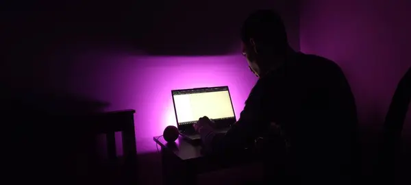 Stüdyoda bilgisayar bilgisayarı olan genç bir siluet menekşe arka planda izole edilmiş. Yüksek kalite fotoğraf