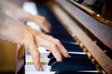 Close up male hand playing piano in the room.