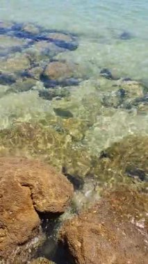 Caparica yakınlarındaki Portekiz plajında, refleks ve taşların yansımaları ile berrak ve temiz su Atlantik okyanusunun dalgalarında dalgalanır.