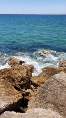 Caparica yakınlarındaki Portekiz plajı, refleks ve taşların yansımalarıyla berrak ve temiz suyun, ufuk çizgisi ile Atlantik okyanusunun dalgaları arasında dalgalanır.