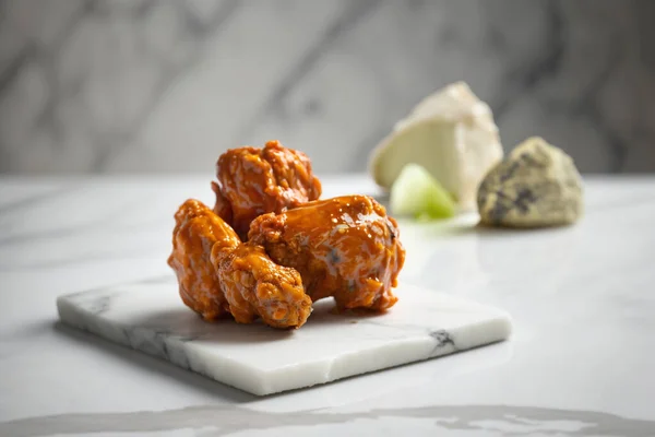 A mouth-watering image of well-prepared buffalo wings served on a wooden platter, captured in high detail with a 85mm lens.