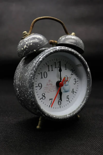 The alarm clock is silver in color, very aesthetic and contrasting in color. It looks vintage because of the slight rust.