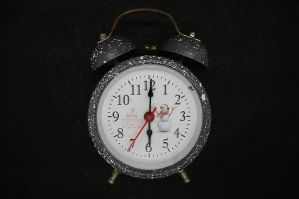 The alarm clock is silver in color, very aesthetic and contrasting in color. It looks vintage because of the slight rust.