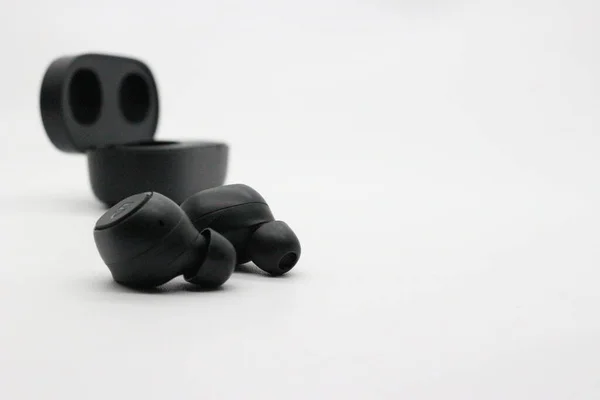 Black bluetooth earphones with white background.