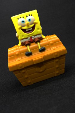 Sünger Bob oyuncağı ve hazine sandığı, siyah arkaplan.