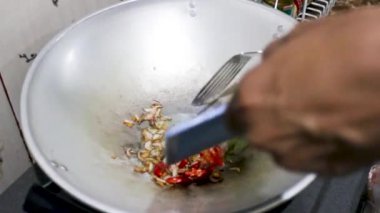 Küçük ve basit bir mutfakta geleneksel bir tavayla baharat pişirmek..