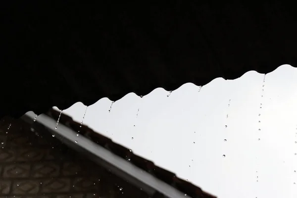 stock image Rainwater falling from the roof of the house at night