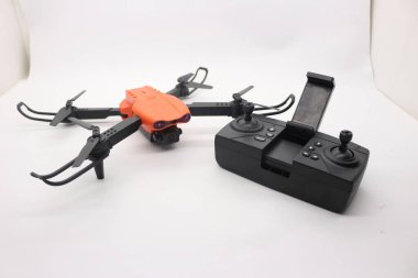 Kameralı turuncu dron ve beyaz zeminde uzaktan kumanda