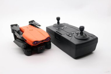 Kameralı turuncu dron ve beyaz zeminde uzaktan kumanda