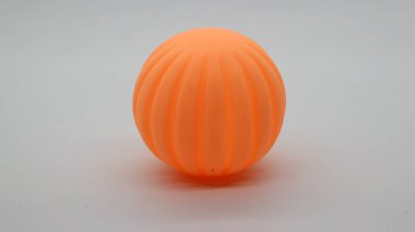 Beyaz arka planda küçük turuncu plastik top oyuncağı