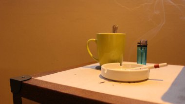 Otel odasında sigara bulunan zarif bir fincan ve kül tablası.