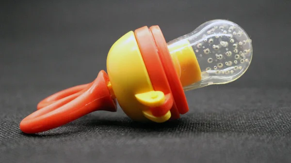 Orange baby pacifier with lid on black background