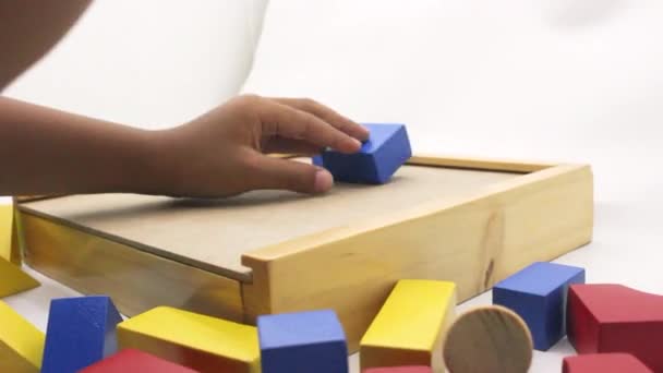 一个孩子把五彩缤纷的木制拼图玩具组装在一个白色的背景上 — 图库视频影像