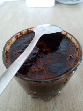 Koyu kahve ve kaşıkla bardaktaki manzarayı kapat