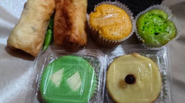 Çeşitli pazar atıştırmalıkları. Çikolatalı kekler, çamurlu kekler, risol ve pandan kekleri var.,