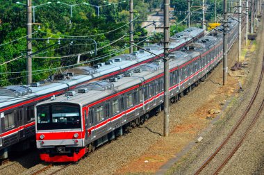 Kırsal ya da tepelik bir alanda hareket eden bir yolcu treni görüntüsü. İki tren hattı ve güzel manzarası var..