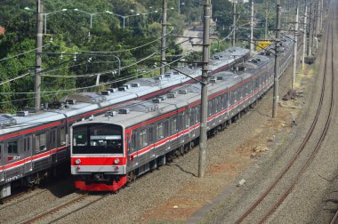 Kırsal ya da tepelik bir alanda hareket eden bir yolcu treni görüntüsü. İki tren hattı ve güzel manzarası var..