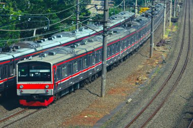 Kırsal ya da tepelik bir alanda hareket eden bir yolcu treni görüntüsü. İki tren hattı ve güzel manzarası var..