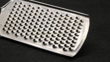 Siyah arkaplanda küçük metal peynir rendesi izole edilmiş