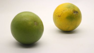 Beyaz arka planlı, yeşil, sarı ve turuncu tenli, Endonezya 'dan portakal meyvesi..