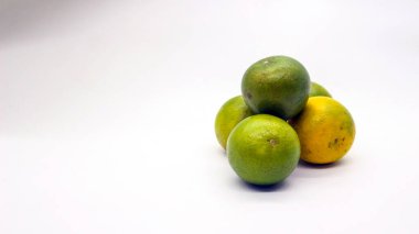 Beyaz arka planlı, yeşil, sarı ve turuncu tenli, Endonezya 'dan portakal meyvesi..