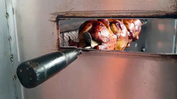 stock image The chicken is being grilled on an automatic rotary grill, it looks like the chicken is already cooked.