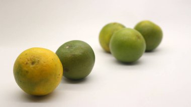 Beyaz arka planlı, yeşil, sarı ve turuncu tenli, Endonezya 'dan portakal meyvesi..