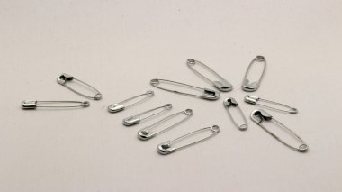 Emniyet iğnesi metalden ve gümüşten yapılmış, beyaz bir arka planı var..