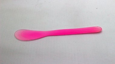 Pembe ve yeşil plastik maske spatulası beyaz arkaplanda izole edilmiş.
