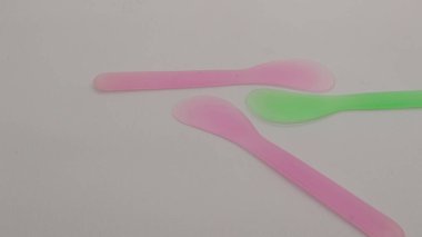 Pembe ve yeşil plastik maske spatulası beyaz arkaplanda izole edilmiş.