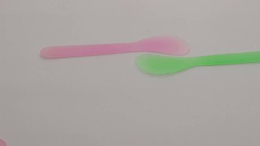 Pembe ve yeşil plastik maske spatulası beyaz arkaplanda izole edilmiş.