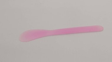 Pembe ve yeşil plastik maske spatulası beyaz arkaplanda izole edilmiş.