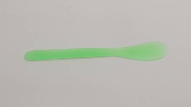 Pembe ve yeşil plastik maske spatulası beyaz arkaplanda izole edilmiş.