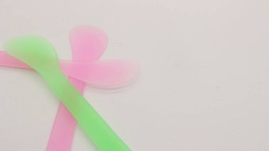 Pembe ve yeşil plastik maske spatulası beyaz arkaplanda izole edilmiş.