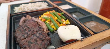 Restoran masasında servis edilen biftek, pirinç ve sebzeleri yakından izleyin.