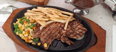 Restoran masasında servis edilen kızarmış patates ve sebzeli tavuk bifteğini kapat.