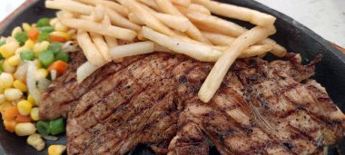 Restoran masasında servis edilen kızarmış patates ve sebzeli tavuk bifteğini kapat.