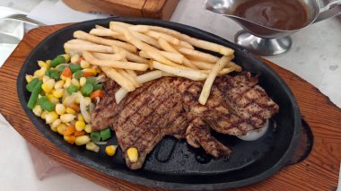 Restoran masasında servis edilen kızarmış patates ve sebzeli tavuk bifteğini kapat.